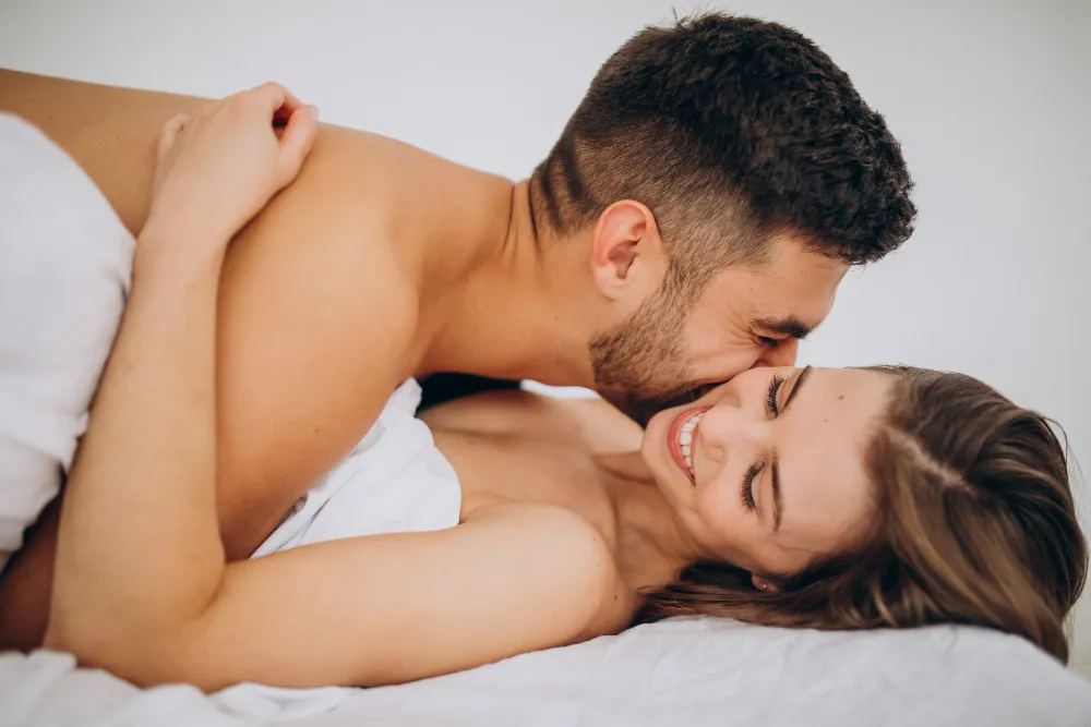 Couple lying together in bed sharing tender intimate foreplay with deep connection